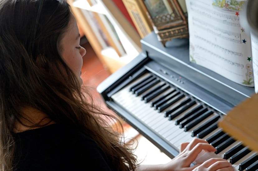 focus on the hands on the keyboard as a young female plays keyboard