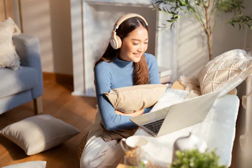 Smiling casual of asian freelance female adult woman sit on floor in living room watching online str...