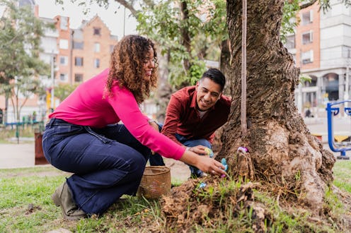Couple hiding chocolate eggs on Easter egg hunt game at the park
