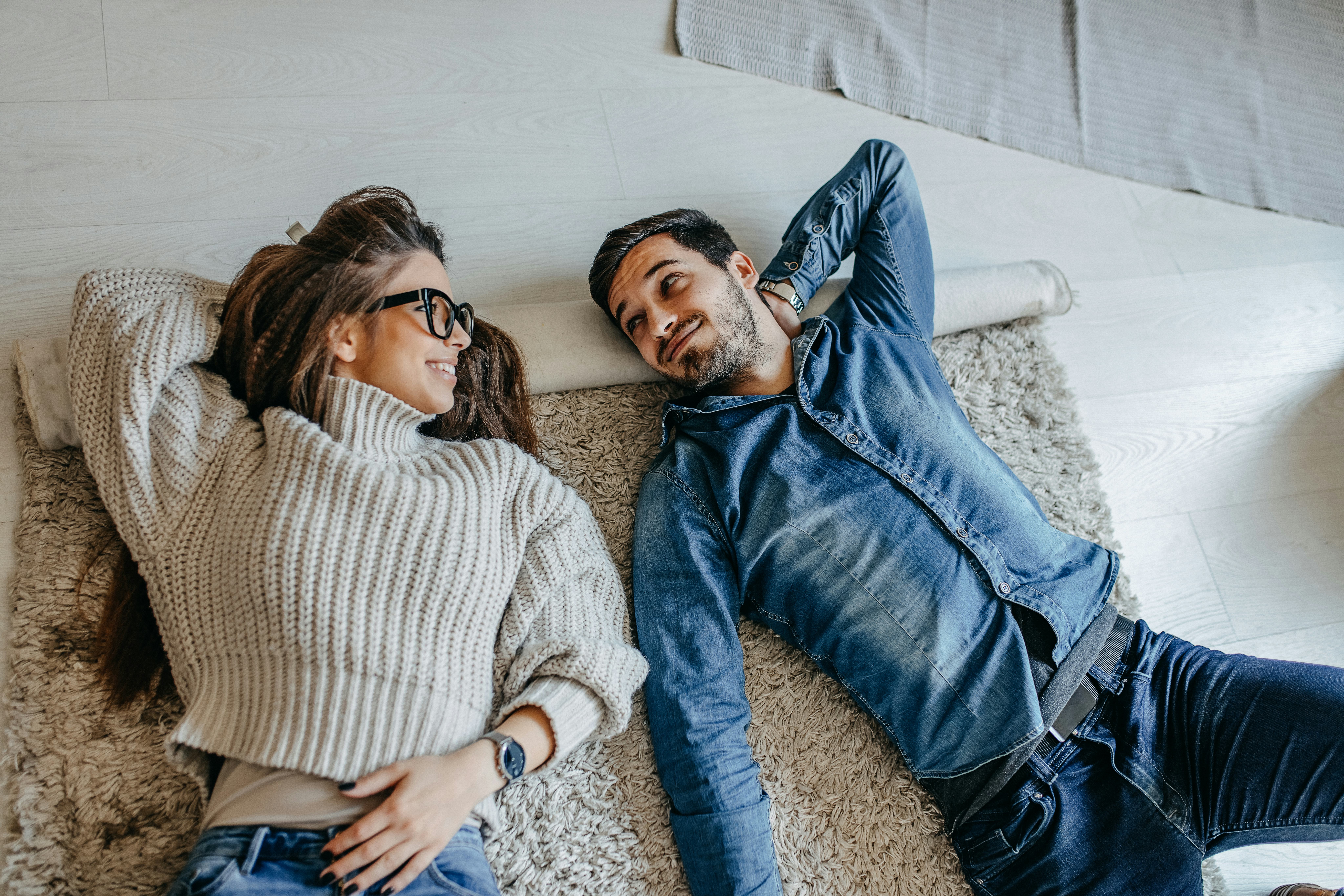 A couple laying on the floor and laughing at some good jokes about relationships.