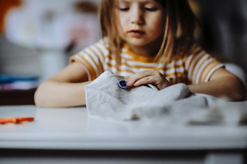 Child girl sewing independently at home, education, children's creativity, and Montessori-inspired f...