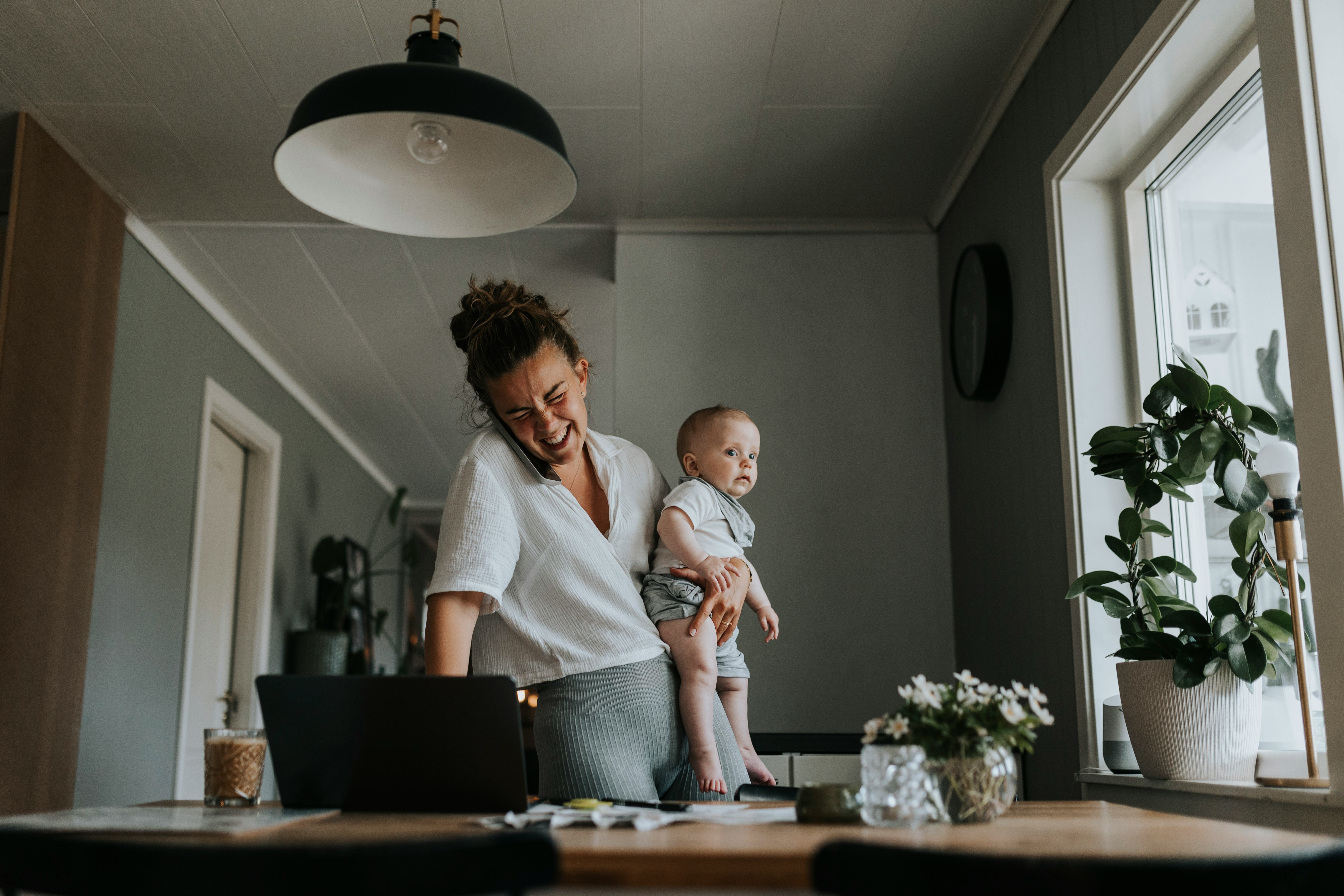 A young woman working from home and taking care of her baby, laughing at good jokes about working fr&hellip;