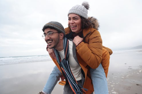 couple playing piggy back on beach in winter