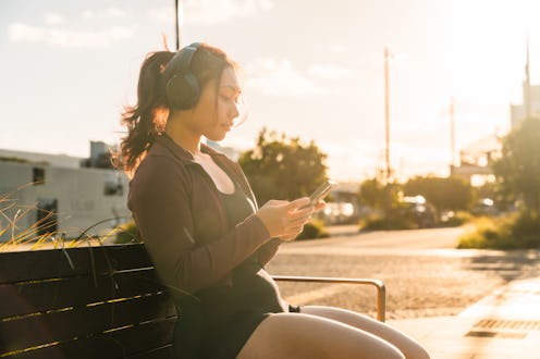 Young pacific islander athletic woman wearing headphones using smart phone.