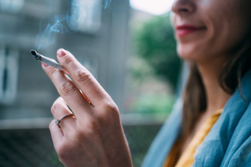 Unrecognizable young woman enjoying a cigarette outdoors. Focus is on the cigarette.