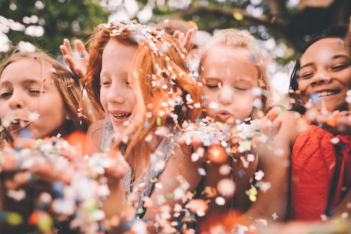 Creative shot of a blurred colourful pieces of paper confetti being blown towards the camera on a su...
