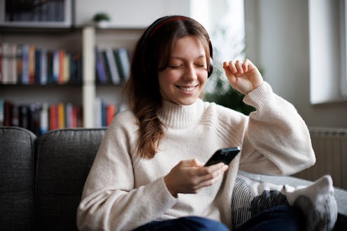 Smiling teenage girl with wireless headphones listening to music at home
