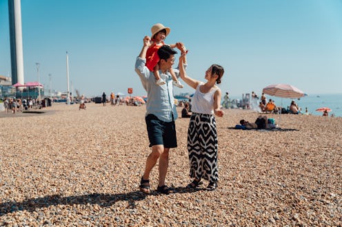 Young Asian family enjoying summer vacation, walking together on the beach. Family love and together...