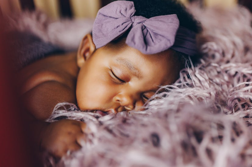 Sleeping newborn with a trendy girl name wearing a purple bow headband