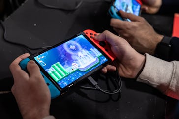 MILAN, ITALY - NOVEMBER 24: Two men use an Oled model Nintendo Switch gaming system while playing vi...