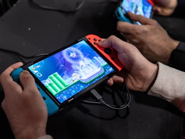 MILAN, ITALY - NOVEMBER 24: Two men use an Oled model Nintendo Switch gaming system while playing vi...