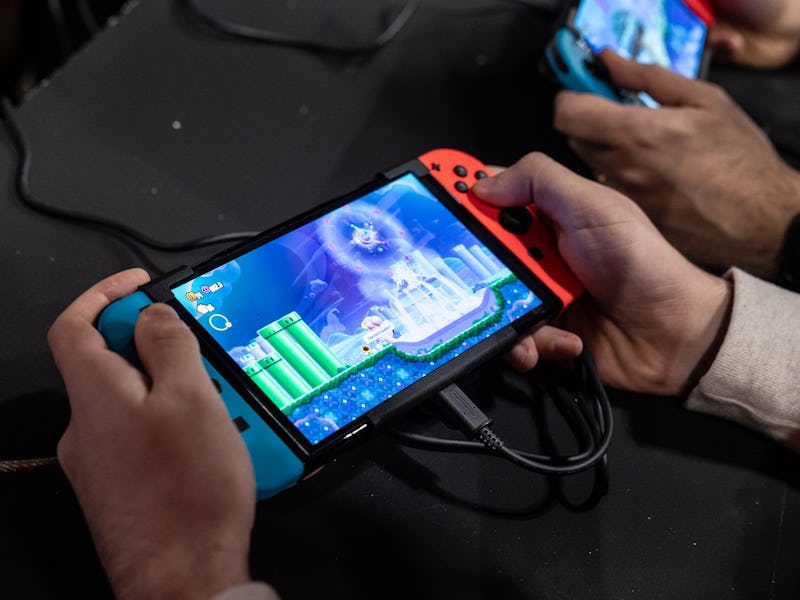 MILAN, ITALY - NOVEMBER 24: Two men use an Oled model Nintendo Switch gaming system while playing vi...