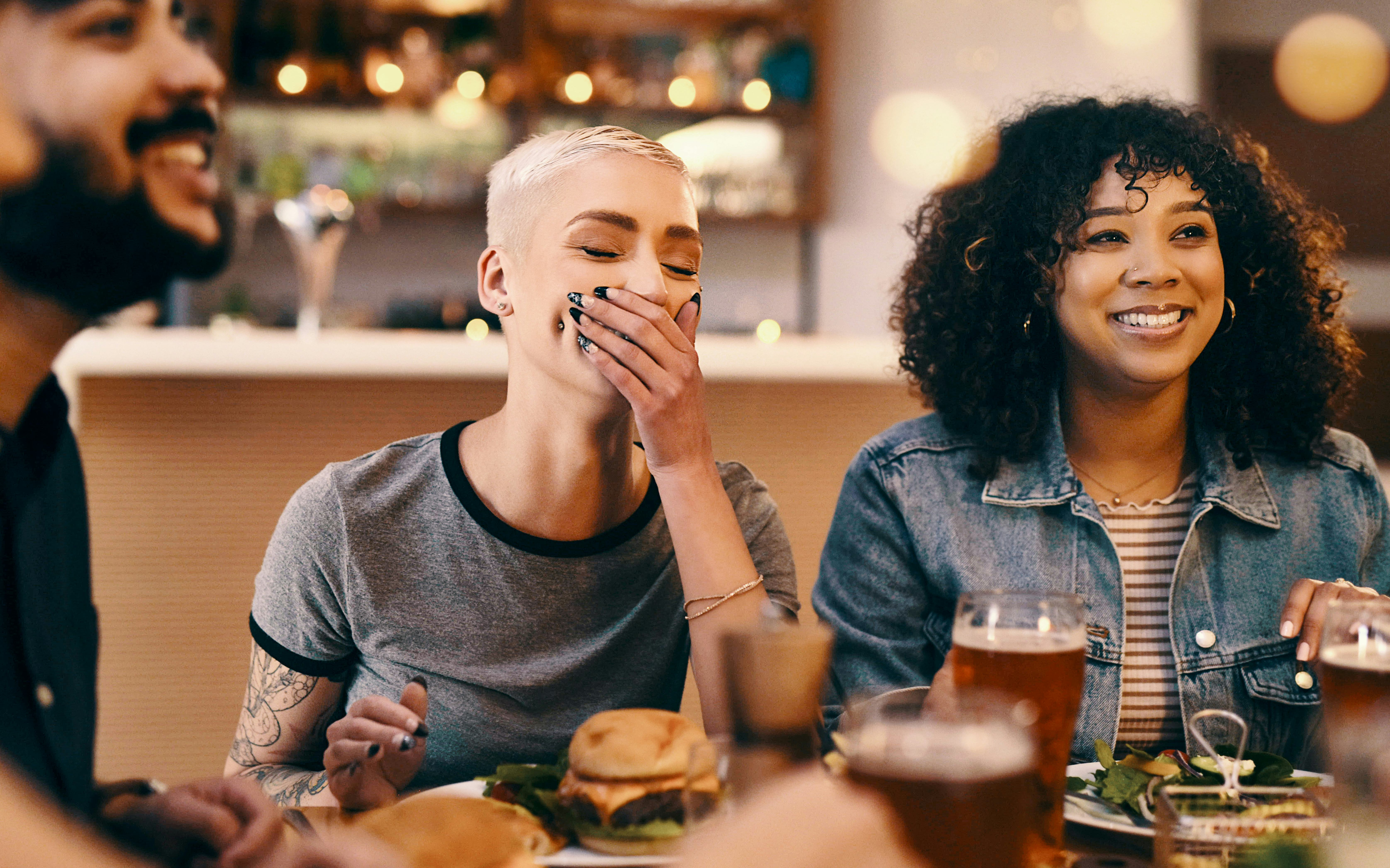 Friends at a table asking funny &ldquo;most likely to&rdquo; questions and laughing