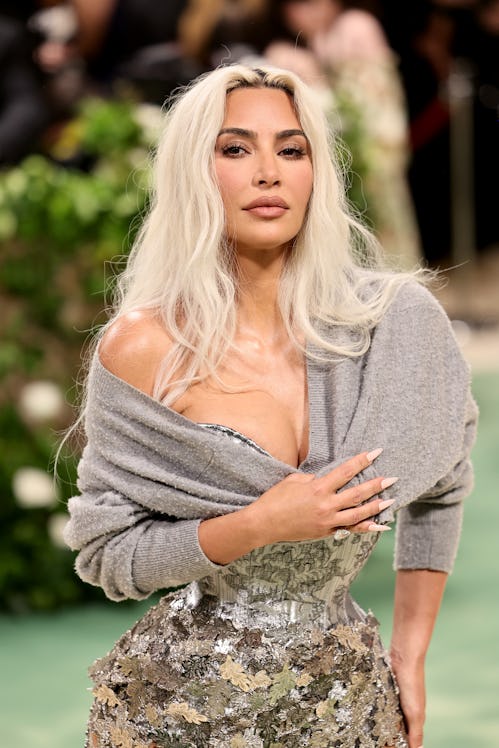 Kim Kardashian attends The 2024 Met Gala in a silver leaf dress and gray cardigan potentially belong...