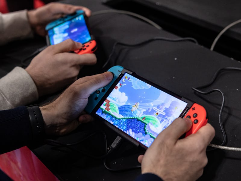 MILAN, ITALY - NOVEMBER 24: Two men use an Oled model Nintendo Switch gaming system while playing vi...