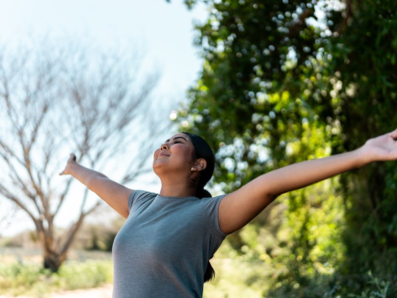 Young woman feeling grateful during hiking on forest