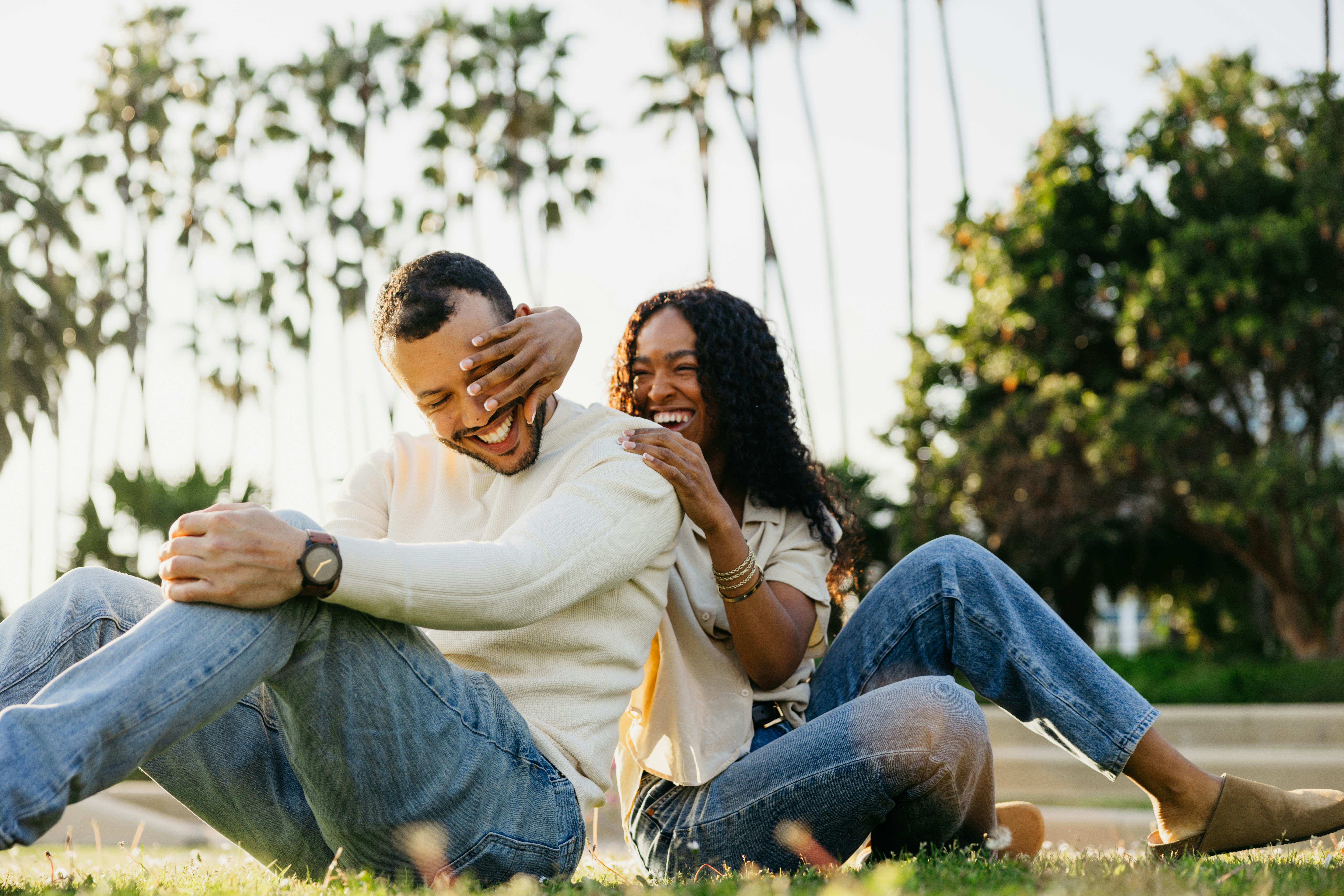 A girlfriend calling her boyfriend funny nicknames as they sit in the park and laugh together.