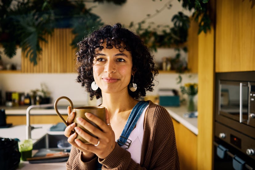 A woman stands in her kitchen holding a coffee mug and contemplates the answers to some tricky riddl…