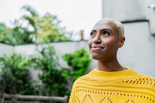 A contemplative young woman in a yellow sweater outside thinking on some hard riddles.