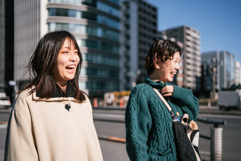 Two young women friends walk in Tokyo and laugh at the simple answers to hard riddles.