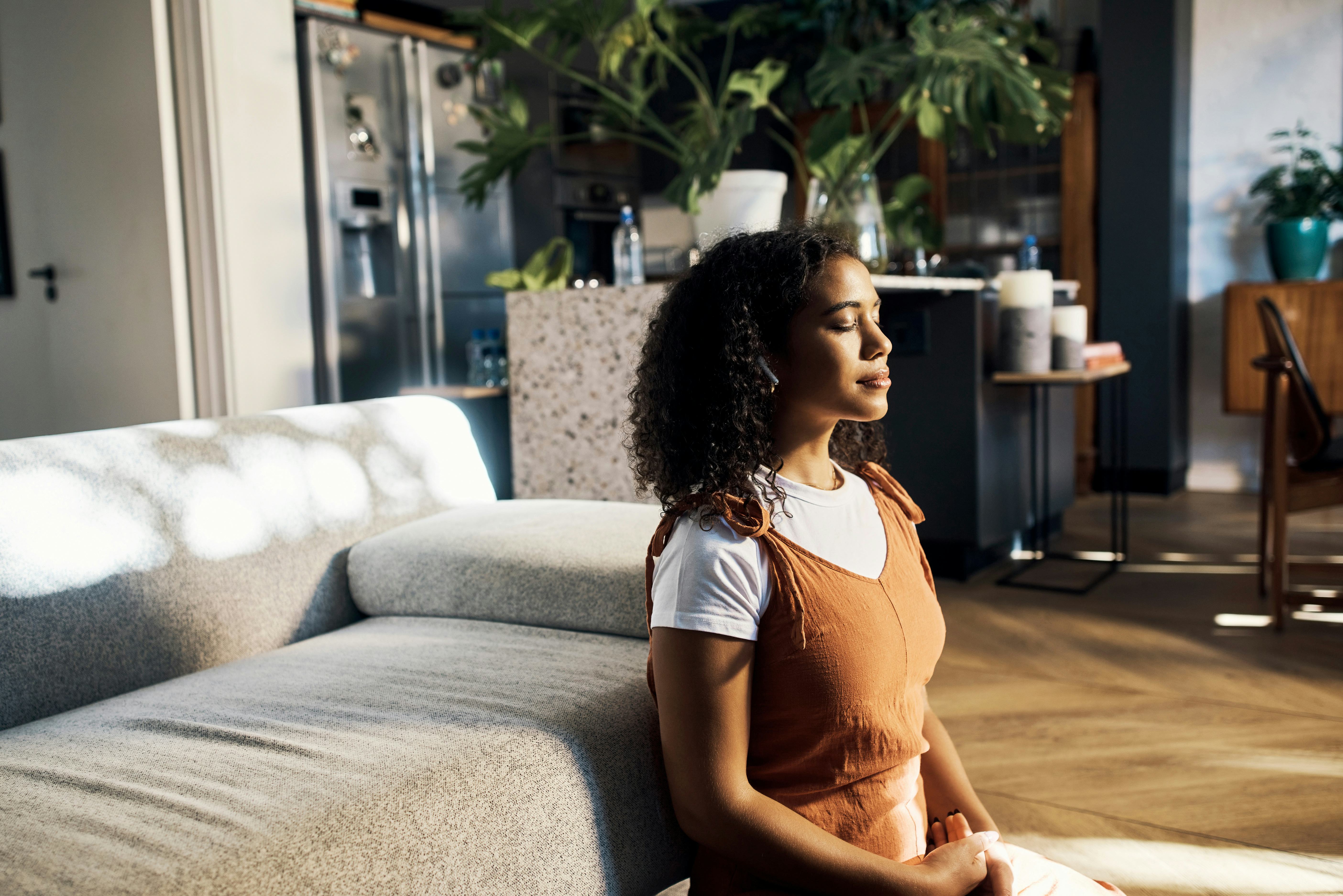 A young woman meditating in her living room thinking up trivia facts.