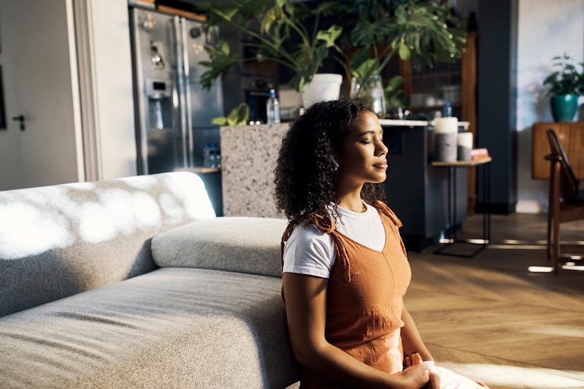 A young woman meditating in her living room thinking up trivia facts.