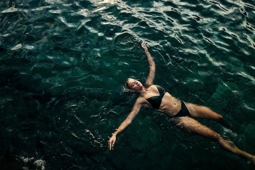 A young woman floating in the ocean thinking about the fun facts she learned about it.