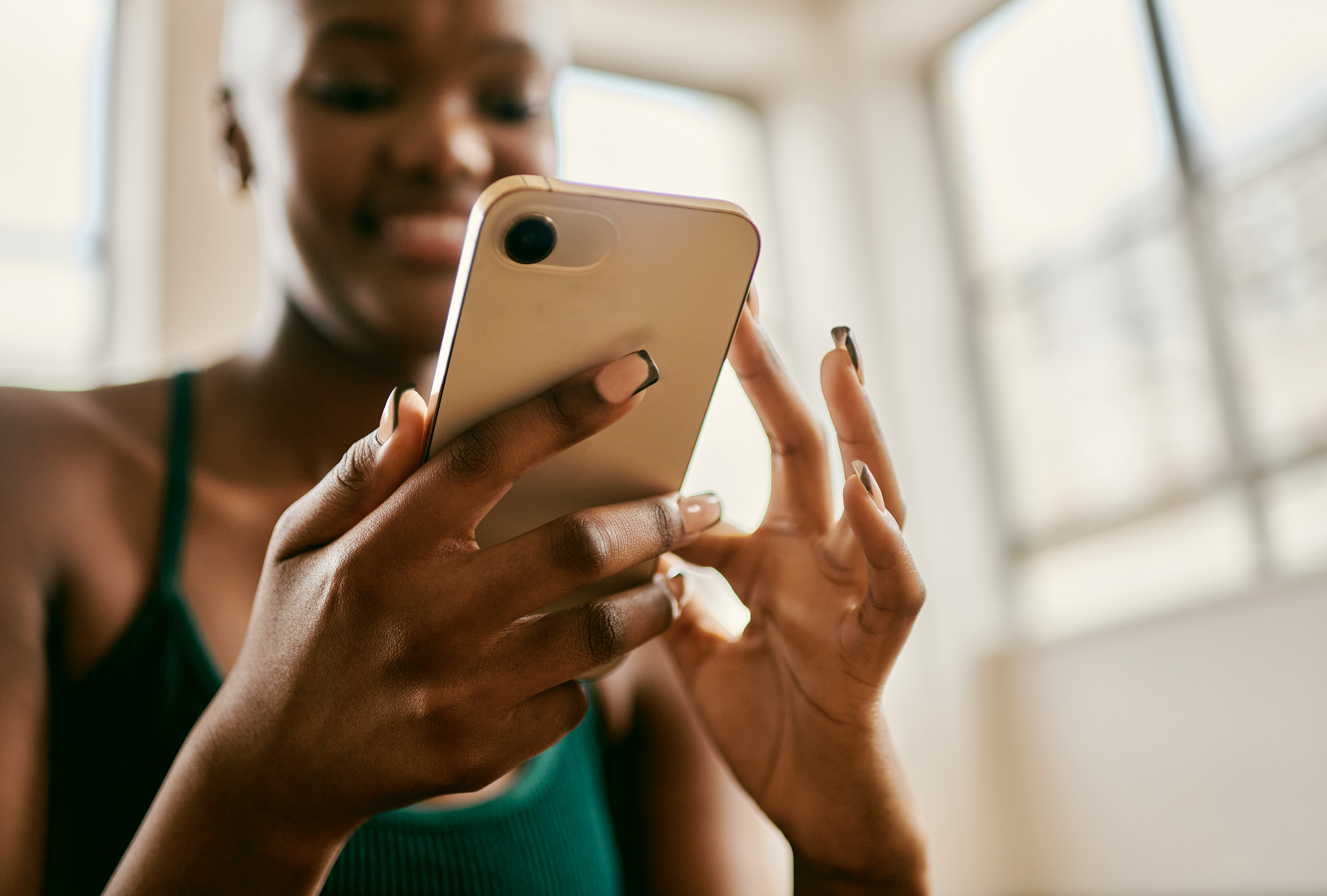 Close up of a woman holding her phone as she reads fun facts about social media.