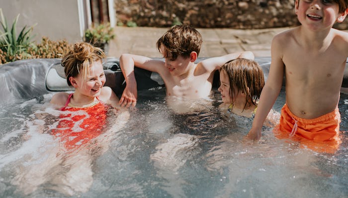 Four children splash and play in a hot tub on a sunny day.