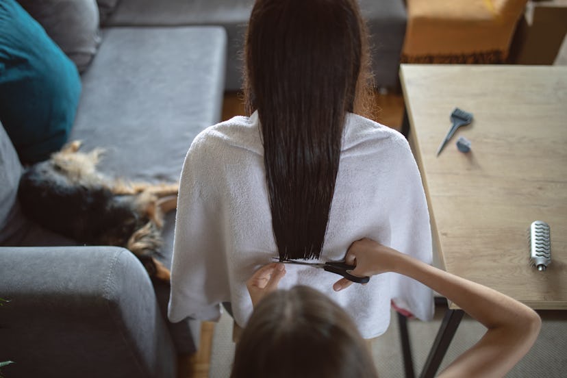 Daughter doing haircut to her mother at home. She has vary long dark hair. They are in living room, ...