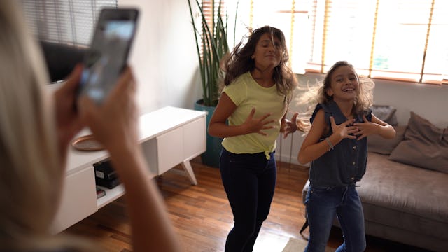 Mother filming teenager daughters dancing at home