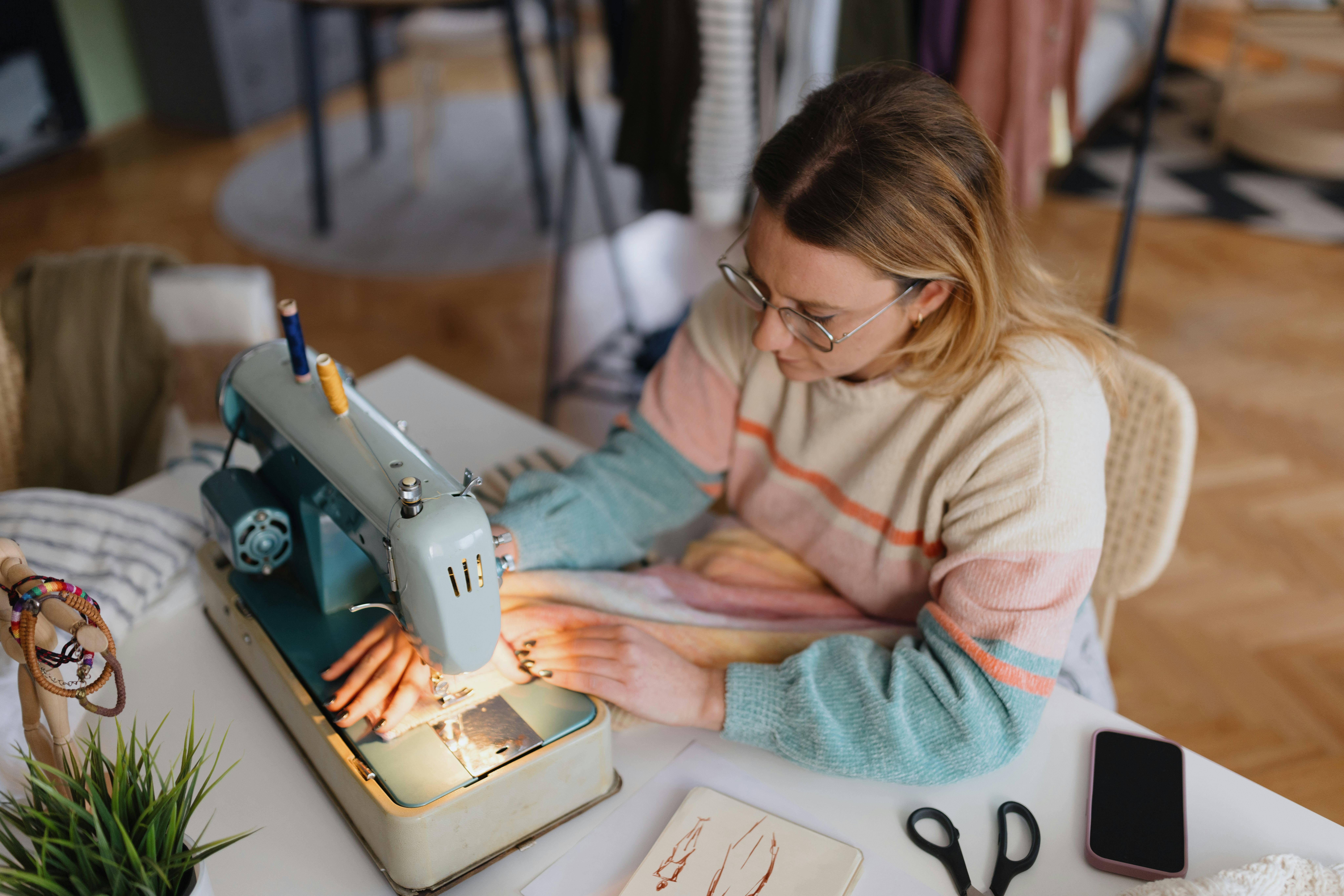 A young woman doing a DIY sewing project at home as she thinks of fun facts about me ideas.