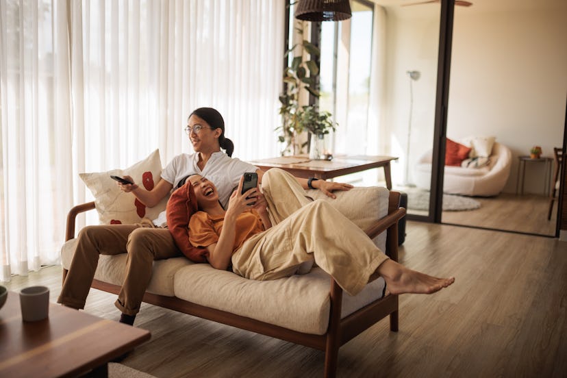 A couple plays the fun facts about me game while they laugh and watch tv on their couch.