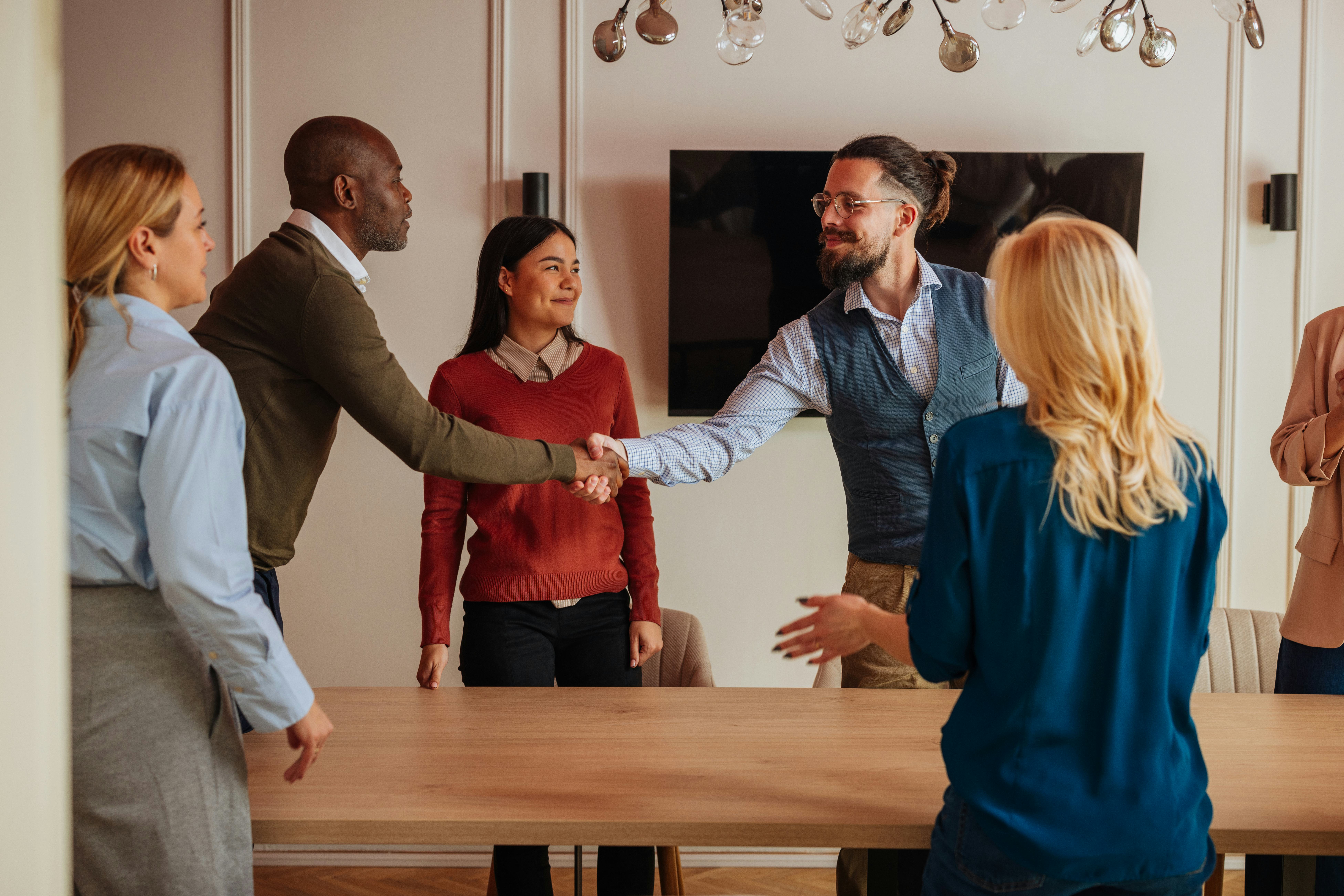 Work colleagues shake hands at a meeting around a table in the office.