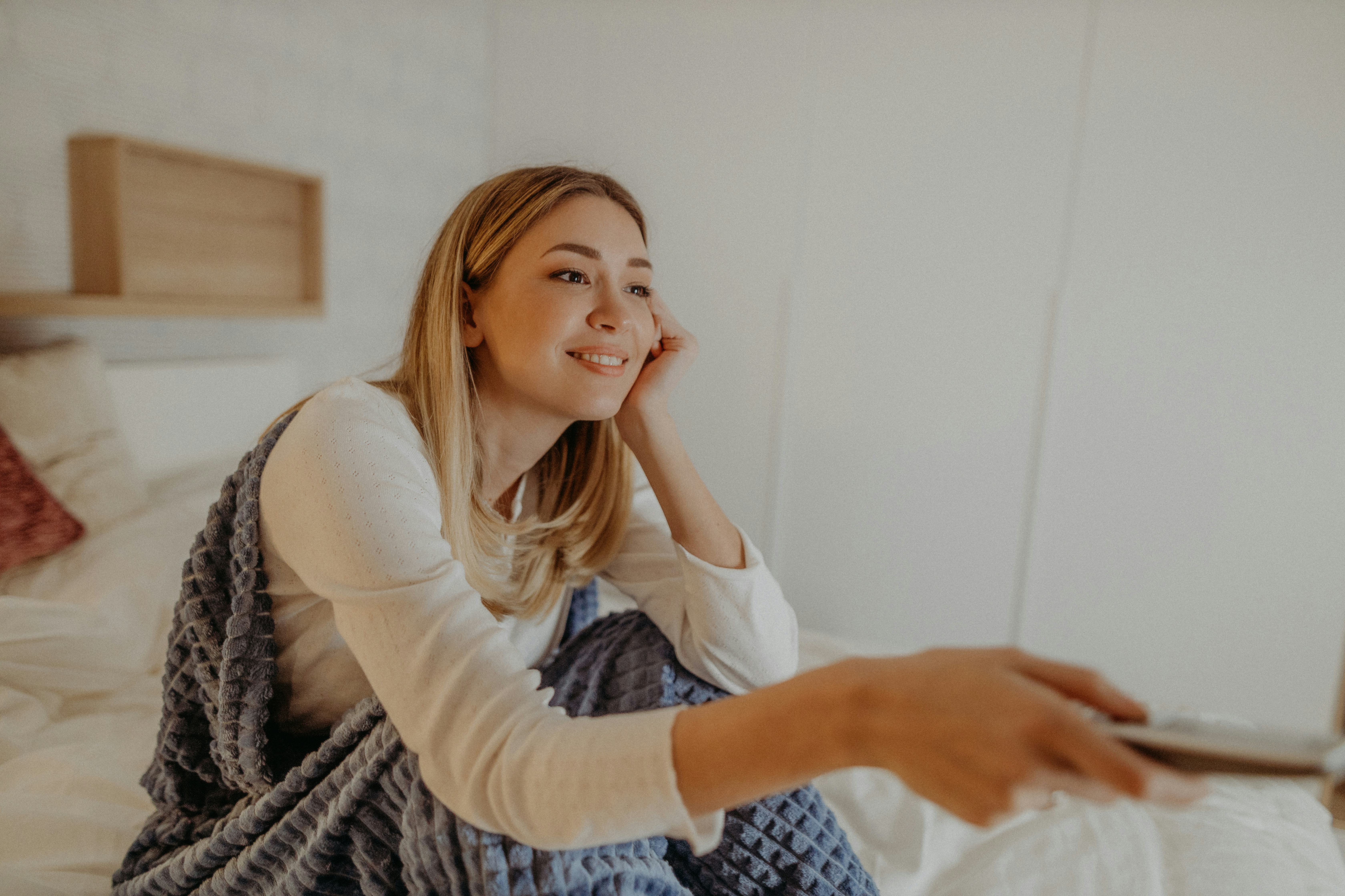 Young woman in her bedroom watching her comfort tv show.