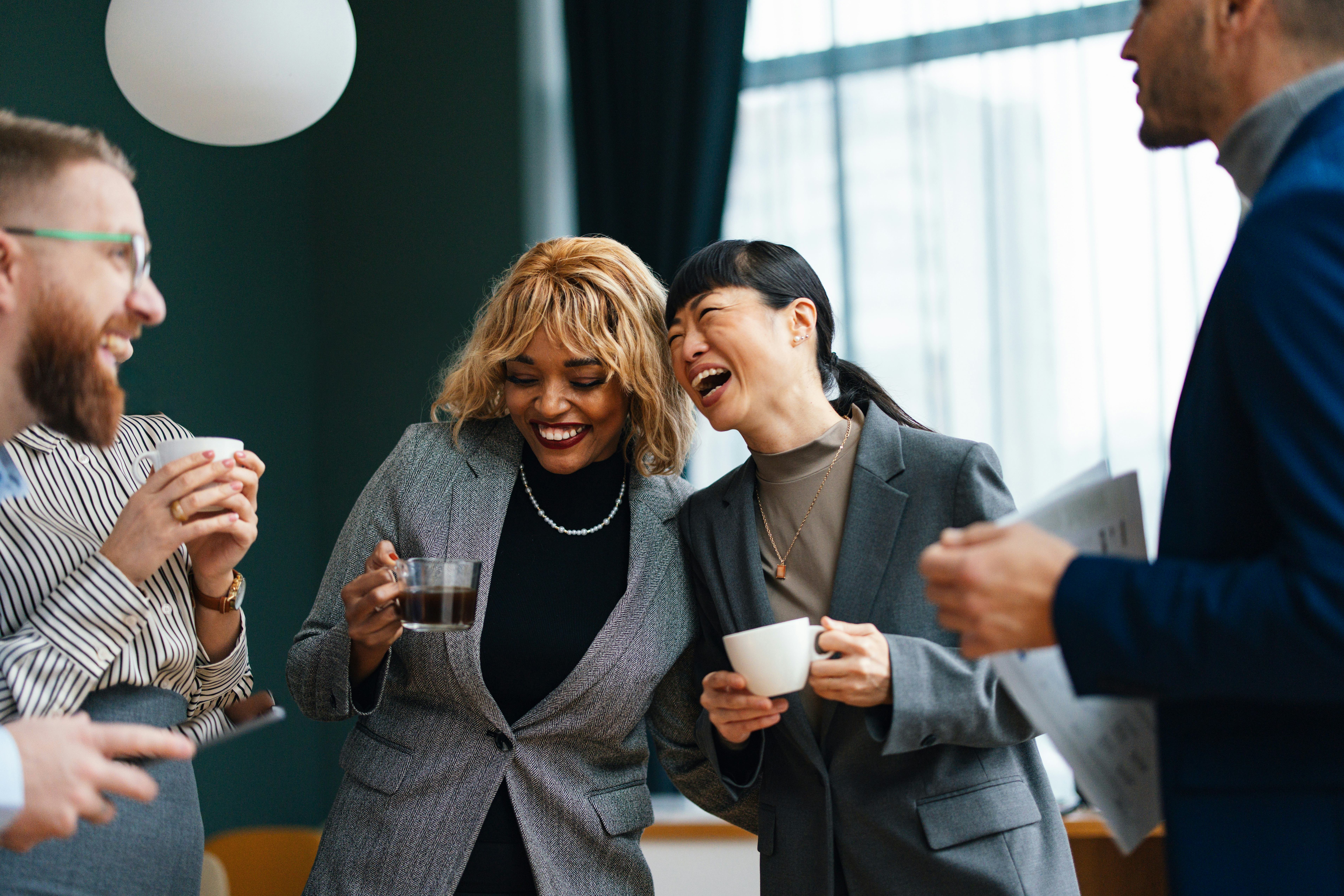 A group of colleagues are laughing in the office at their coworker&rsquo;s fun facts about me answers.