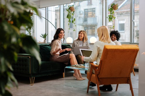 A group of women colleagues sit in the company lounge and play the "fun facts about me" game to get ...