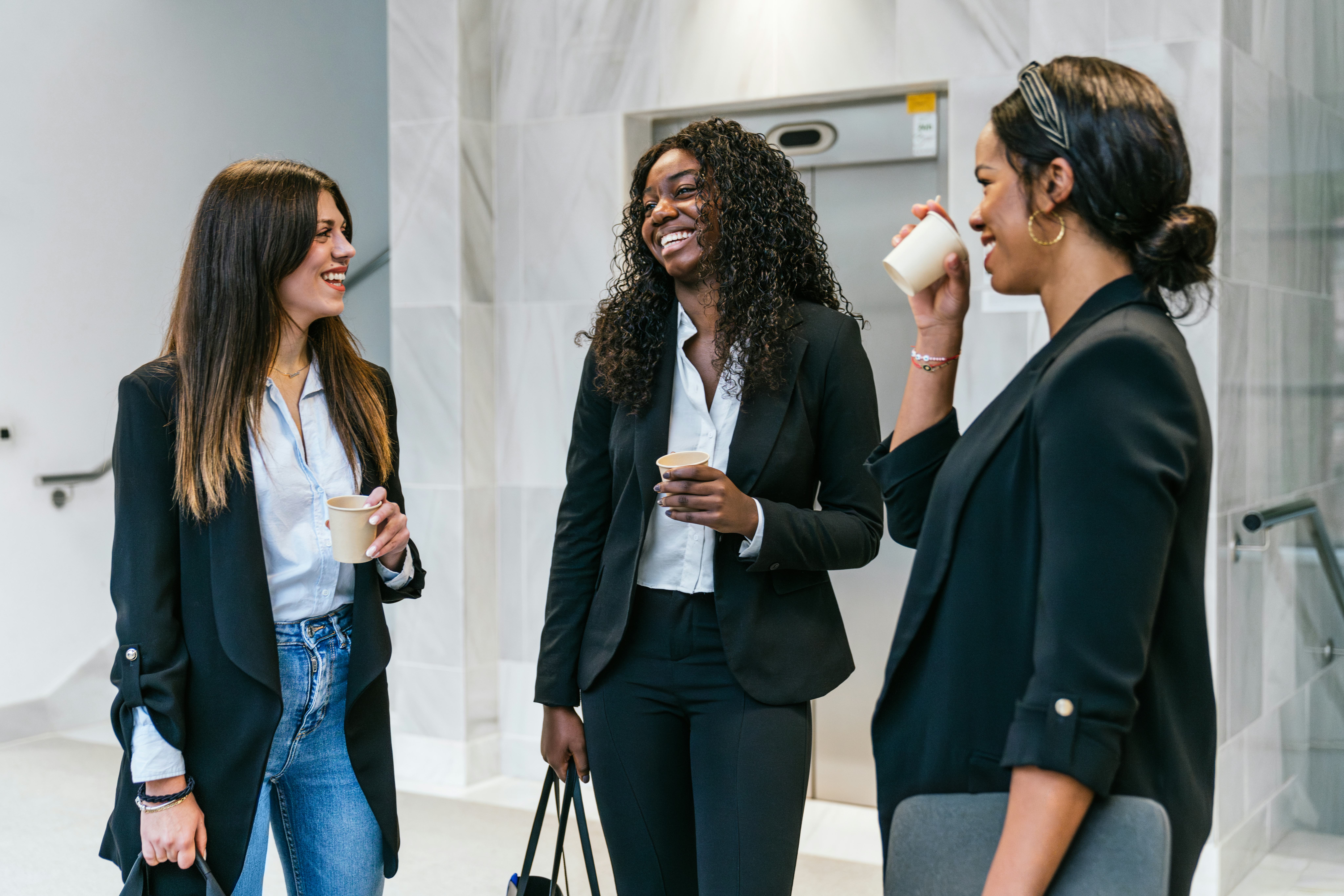 Three young woman tell each other interesting fun facts about themselves at work.