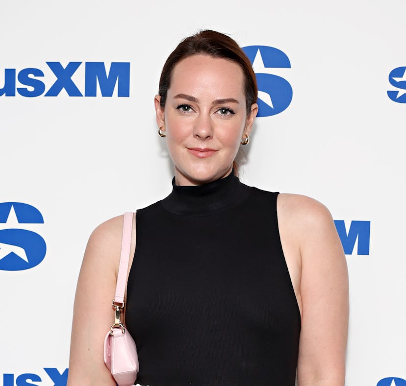 Woman in black turtleneck and pink purse posing in front of a SiriusXM backdrop.