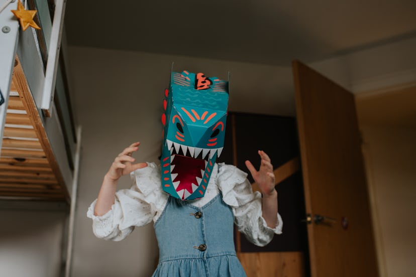 A child pretends to be a dinosaur in a blue din