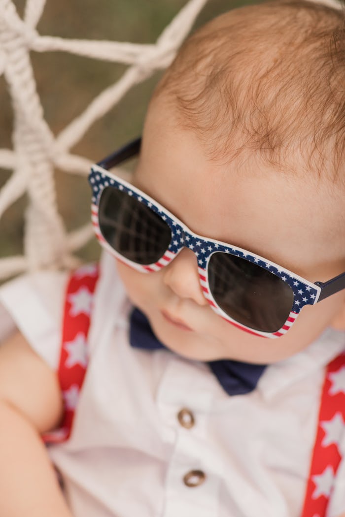 A 6-Month-Old Baby Boy Wearing Red, White & Blue Sunglasses, a Blue Bow tie, Red Star Suspenders & a...