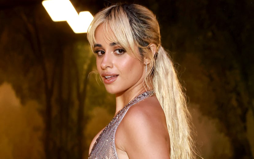 A woman with blonde hair in a shimmering silver gown looks over her shoulder with a subtle smile.