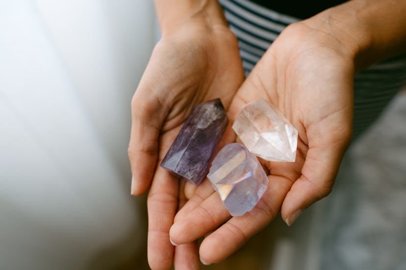 A close up of a woman's hands holding three healing crystals to use at cat names inspiration. 