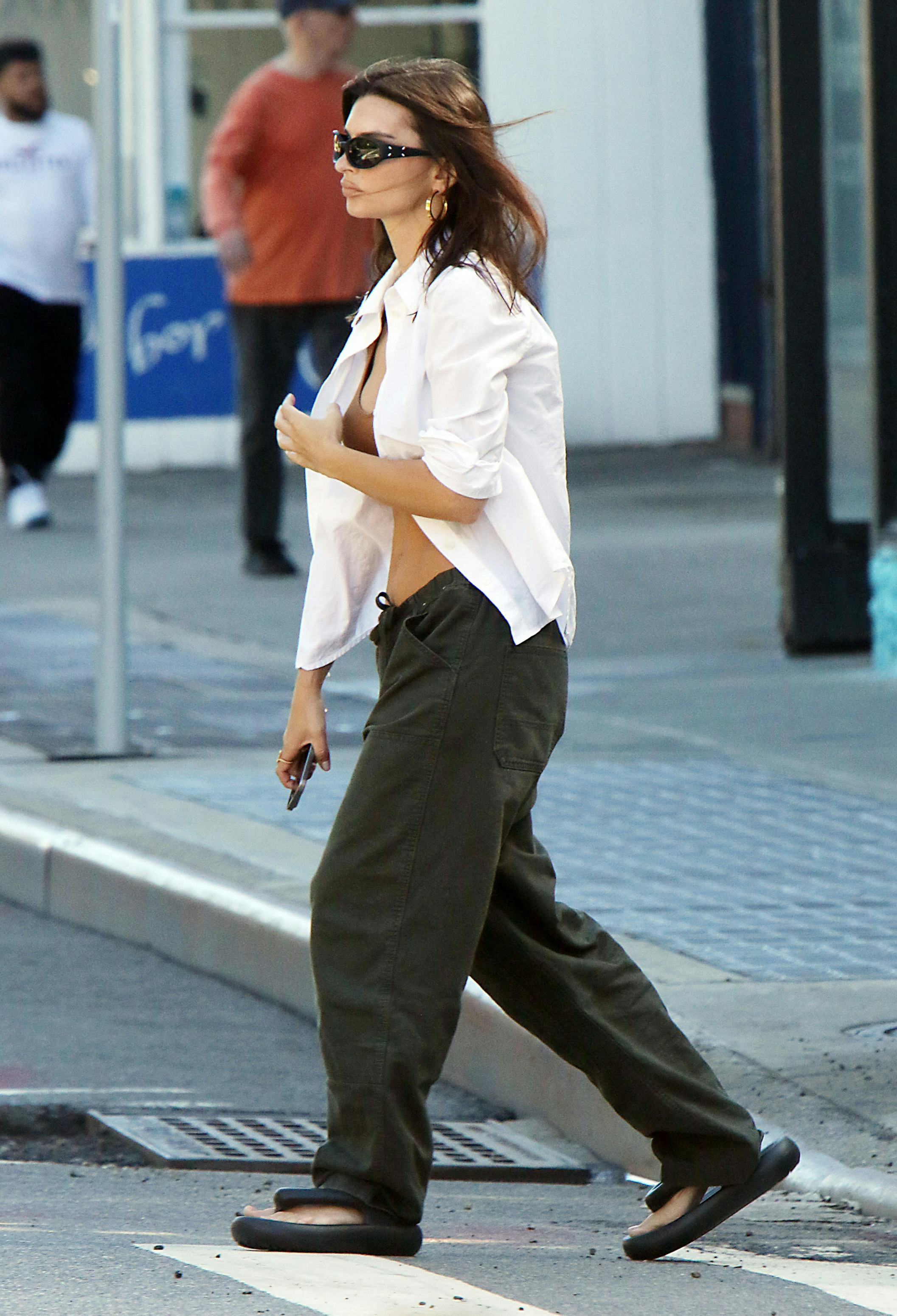 Emily Ratajkowski wears a brown bra, white button-down, and parachute pants in SoHo on June 27, 2024&hellip;