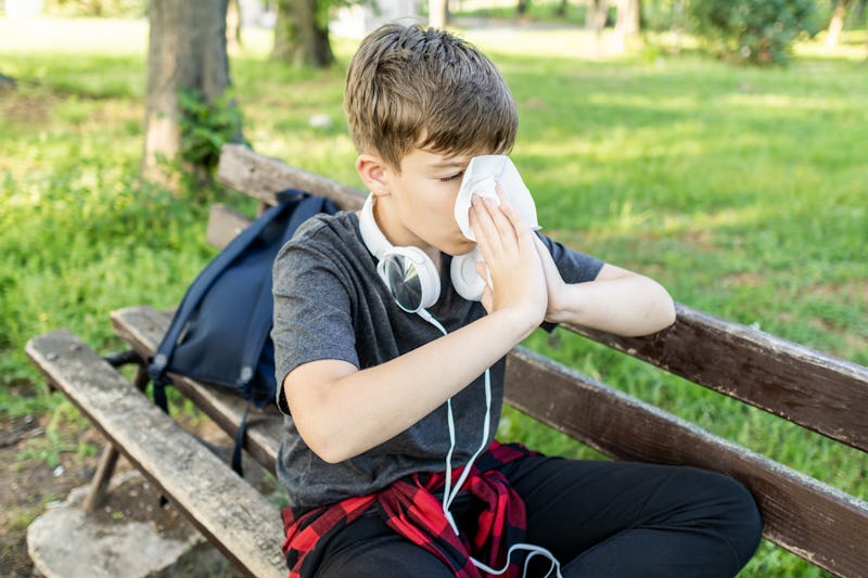 Springtime, allergies, asthma, cough. Boy is using asthma inhaler and nasal spray during an asthma a...