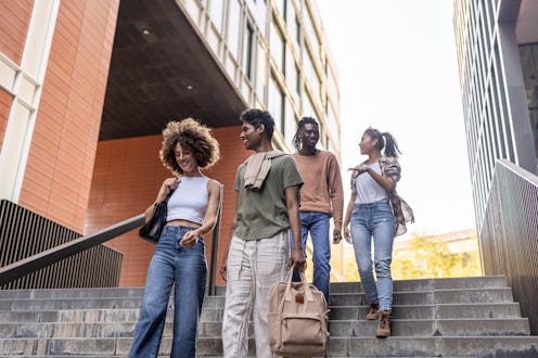 A group of young people are walking up a set of stairs, with one of them holding a backpack. Scene i...