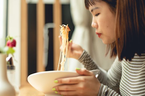 Female portrait of a asian woman who eating noodles in a restaurant. Lifestyle photography with beau...