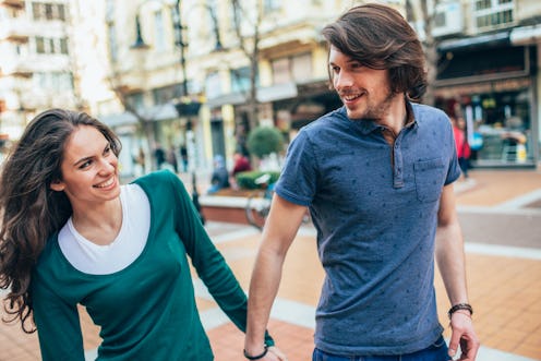 Happy couple having date walking and holding hands. Young couple walking outdoor in the city looking...