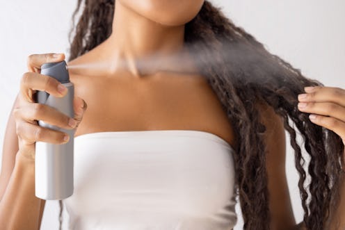 Woman putting hairspray on her hair