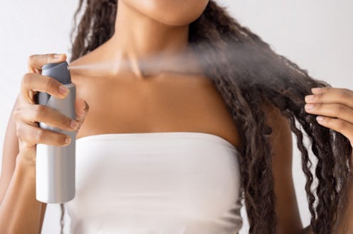 Woman putting hairspray on her hair